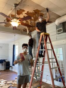 Volunteers on Ladders removing old ceiling tiles